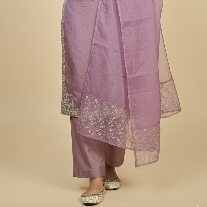 Woman wearing a purple traditional outfit with lace details on a beige background
