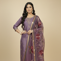 Woman wearing a purple saree with floral patterns on a beige background